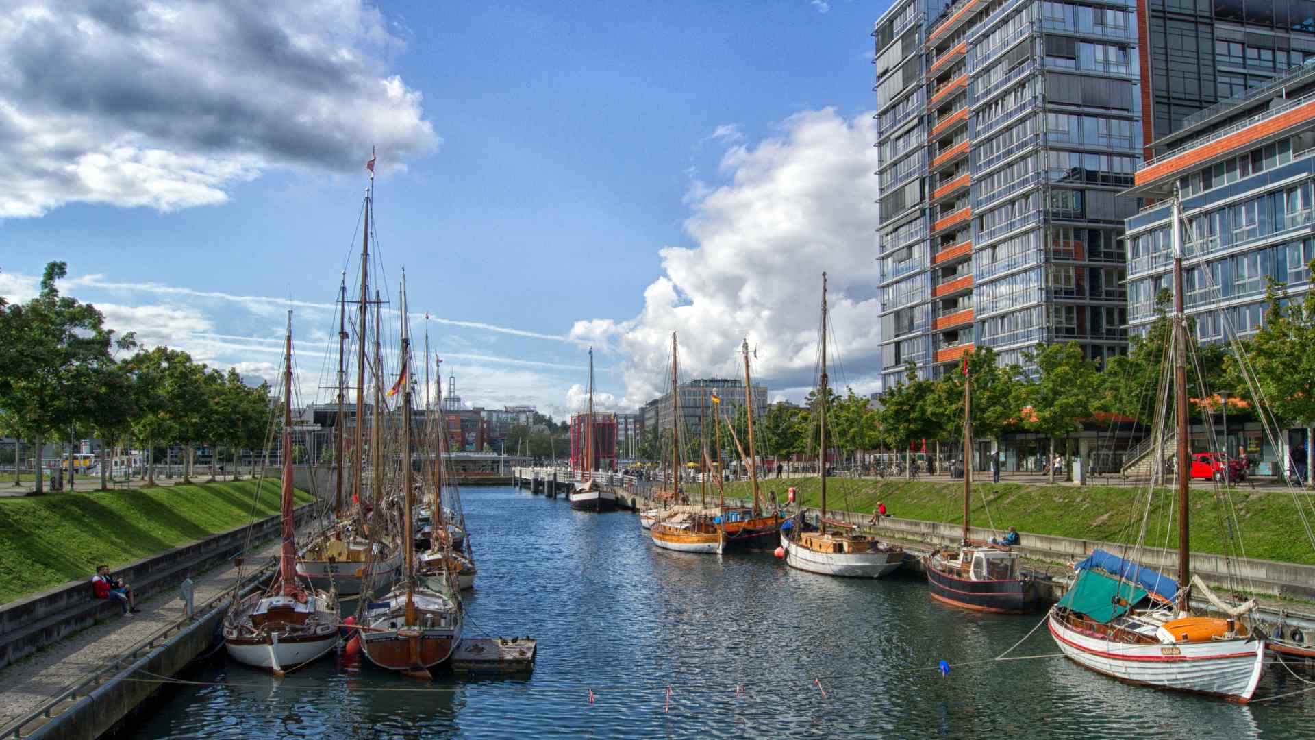 Sailboats moored in Kiel marina beside modern buildings