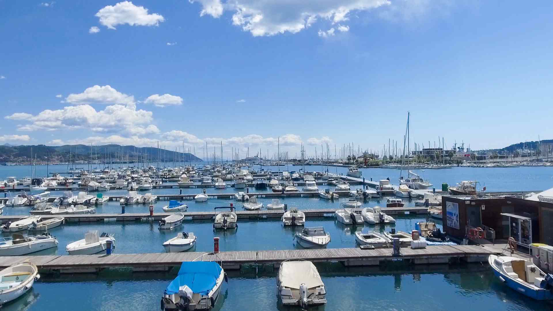 Yachts moored in La Spezia marina beneath coastal hills