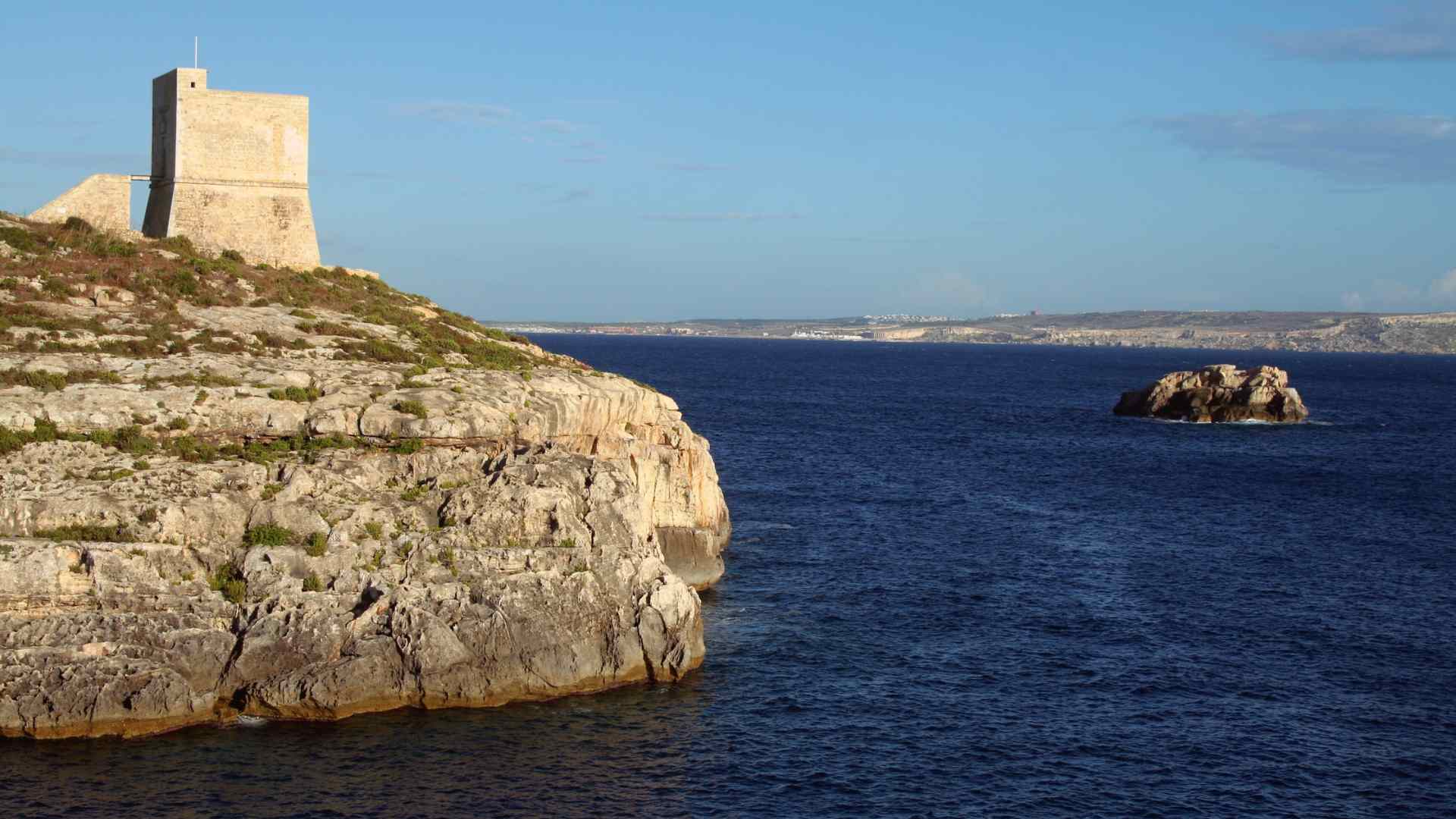 Stone coastal watchtower above a rocky Mediterranean cove
