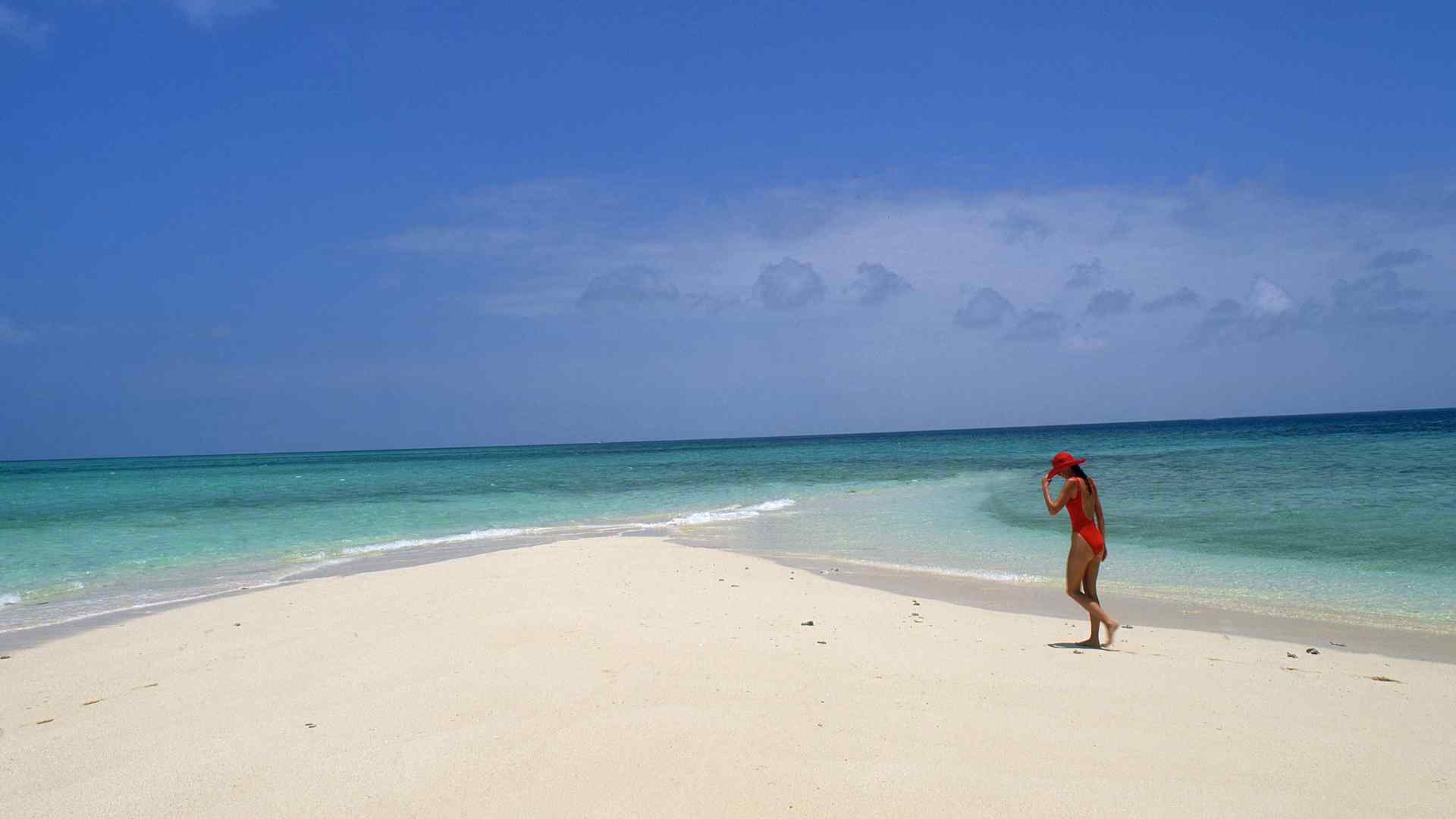 Visitor walking on a white sand beach at Ocean Cay