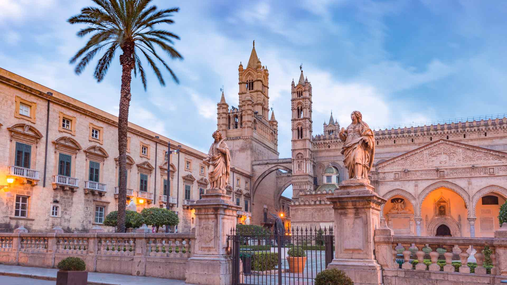 Historic church facade, statues and palm trees in Palermo