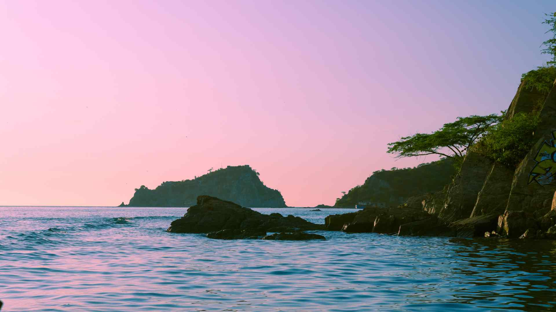 Rocky cove near Santa Marta beneath a pink sunset