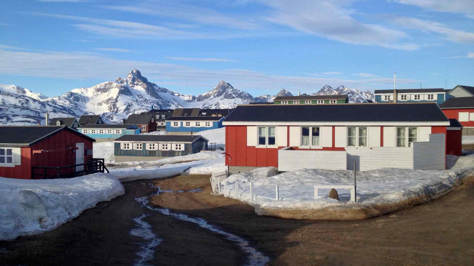 Waterfront buildings beneath jagged mountains in Tasiilaq