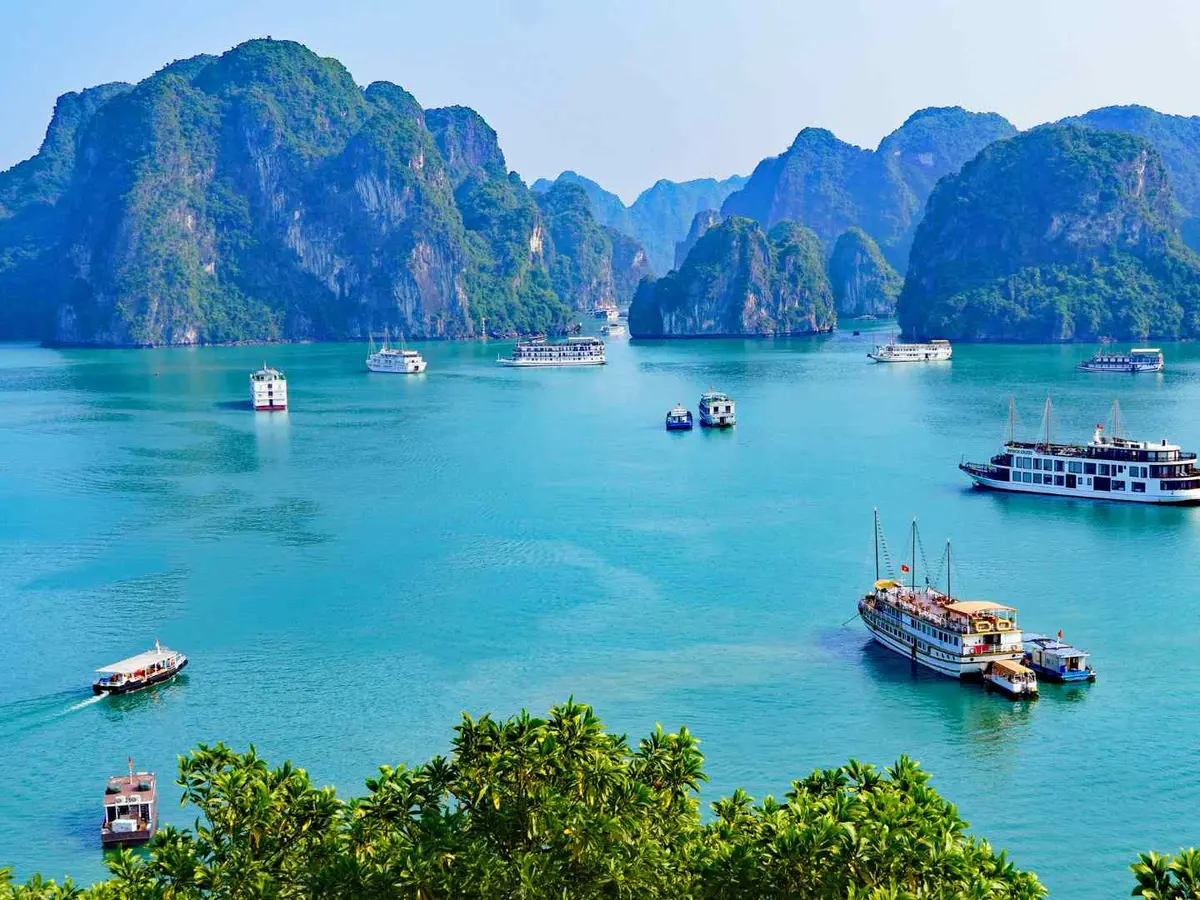 Tour boats cruising among Ha Long Bay limestone karsts in Vietnam