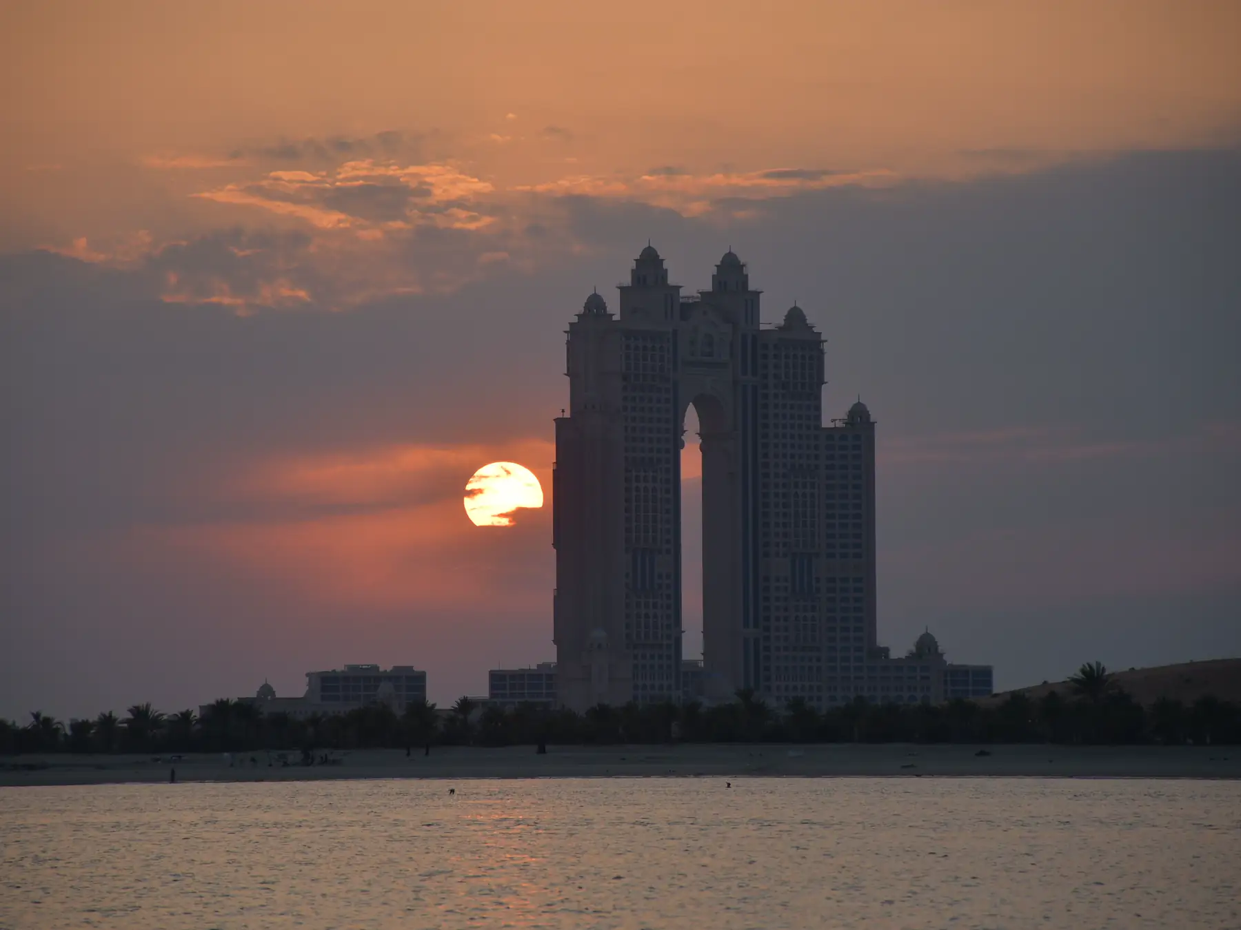 Abu Dhabi skyline silhouetted against a colorful sunset