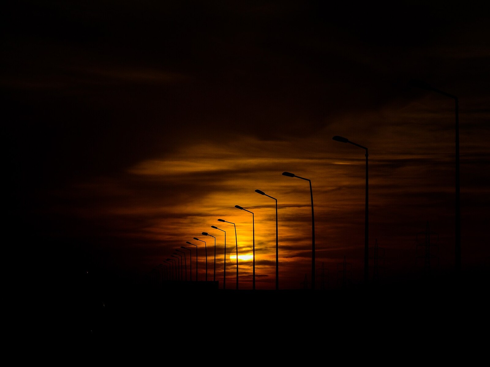 Golden sunset silhouetting a row of streetlights in Ain Sokhna, Egypt
