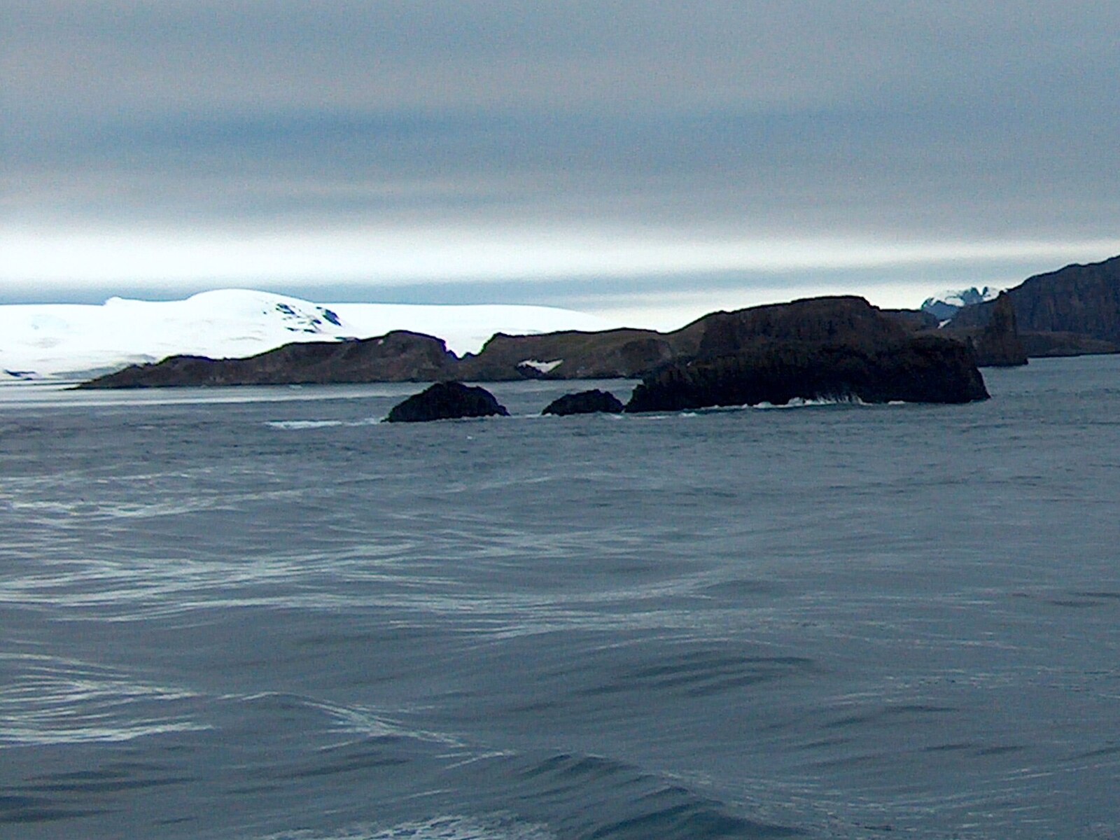 Teteven Glacier and snow-covered islands viewed across calm water from the Aitcho Islands