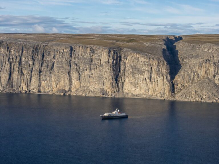 Expedition ship anchored beneath the flat-topped limestone cliffs of Akpatok Island