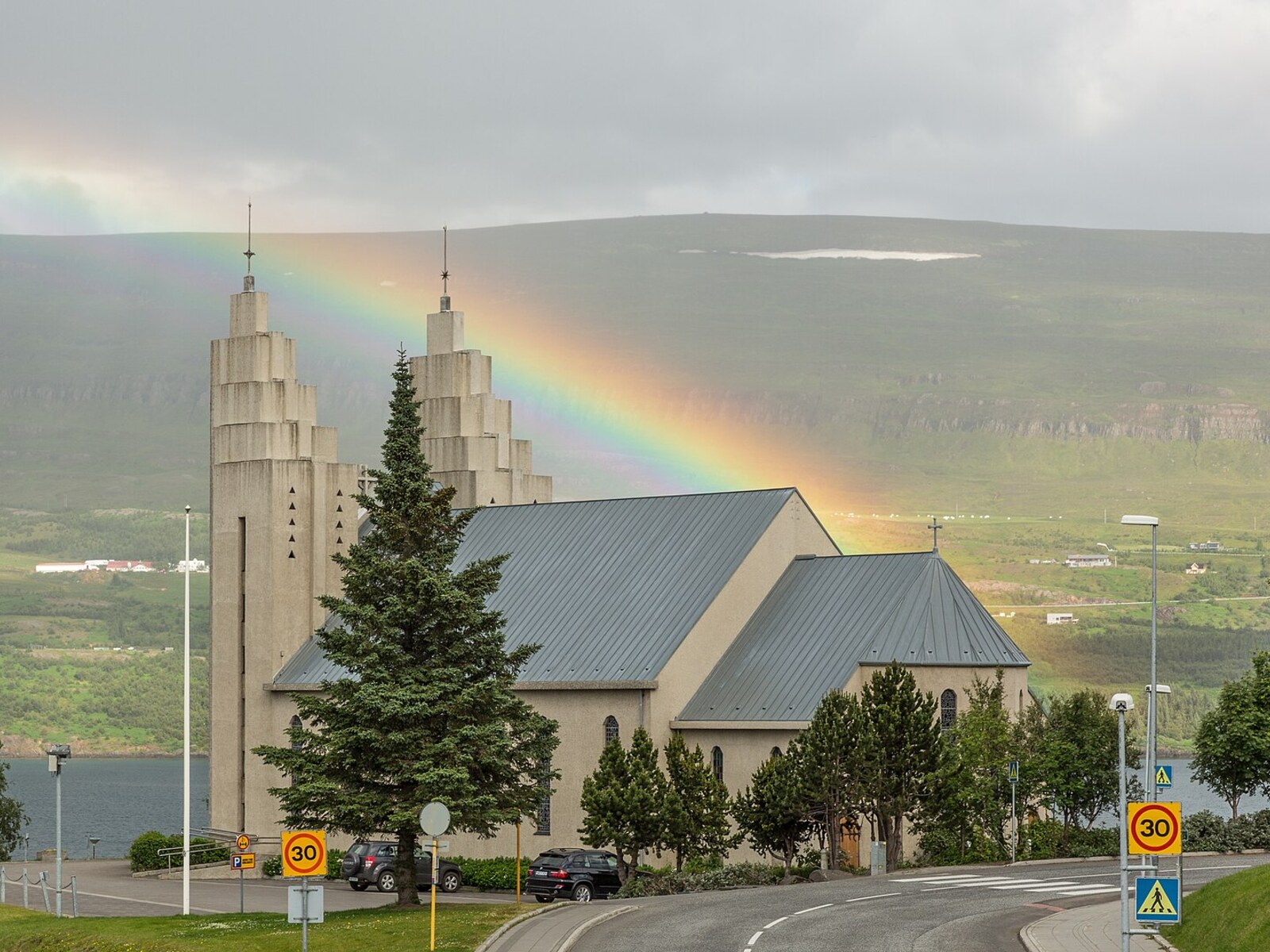 A rainbow arching behind Akureyrarkirkja church in Akureyri, Iceland
