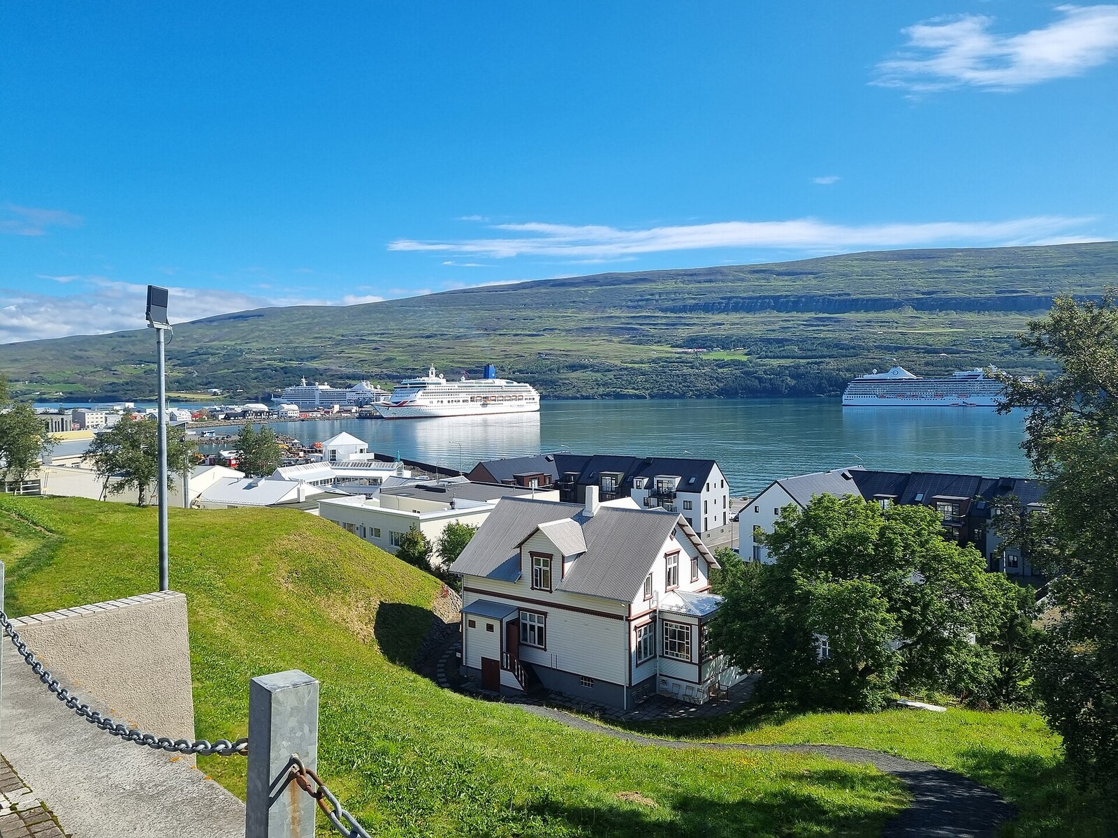 Akureyri city and cruise harbor beside Eyjafjörður with green mountains under a blue sky