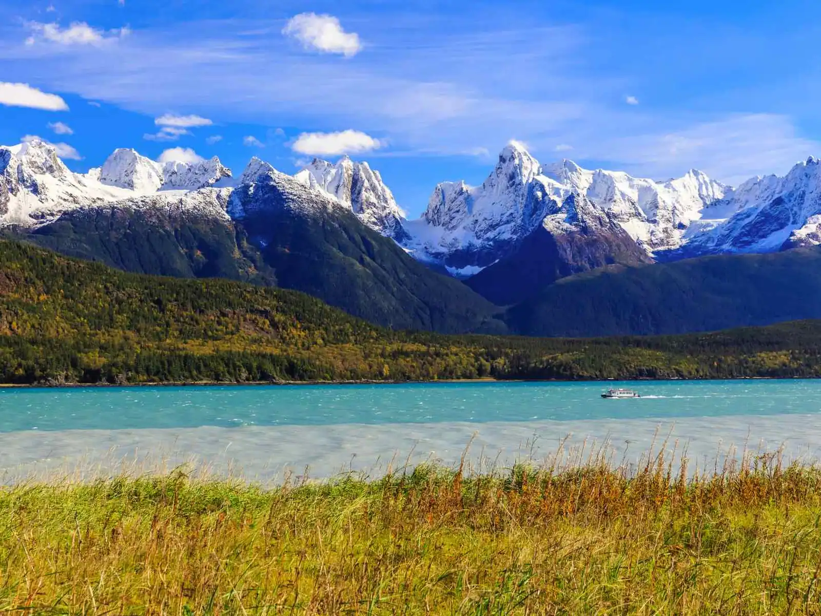 Turquoise lake beneath rugged snow-covered mountains near Skagway