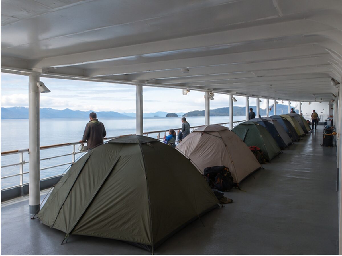 Travelers' tents arranged under the covered solarium deck of an Alaska ferry