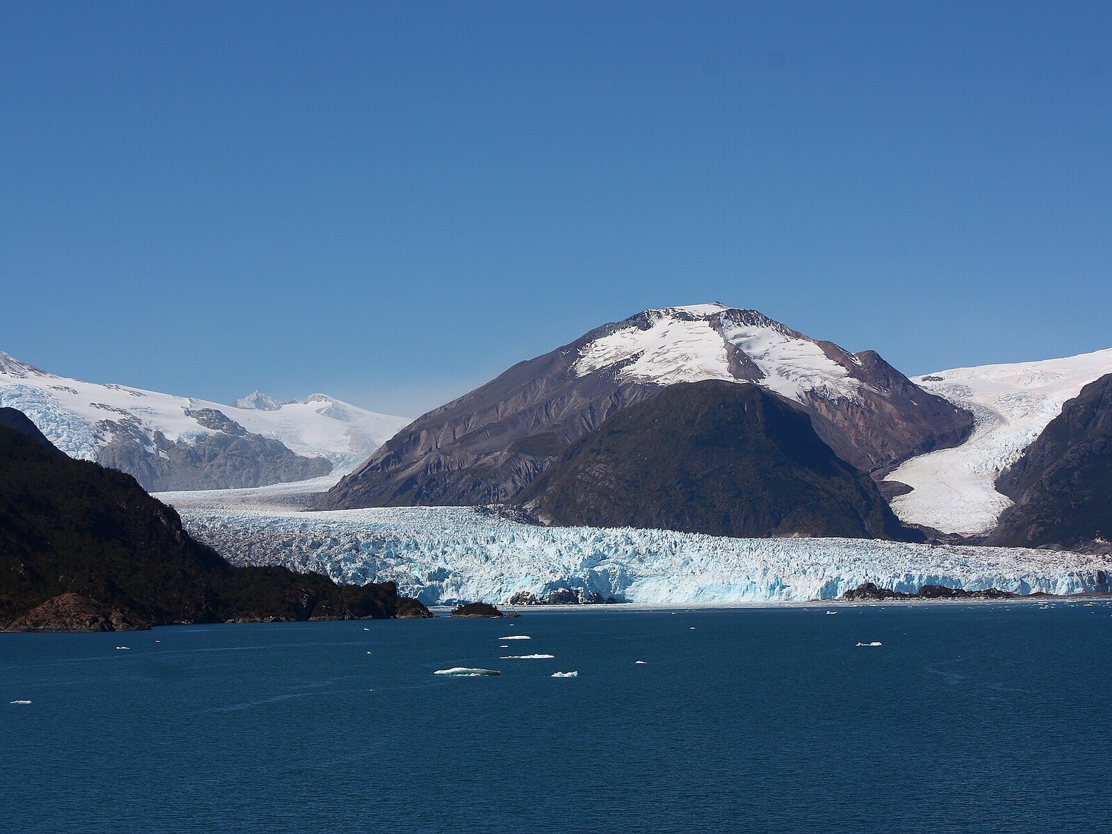 Wide view of Amalia Glacier and snow-covered Reclus Volcano across a deep blue Patagonian fjord