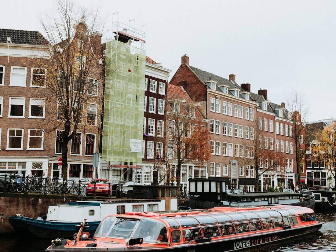Glass-roof canal cruise boat passing Amsterdam's historic waterfront