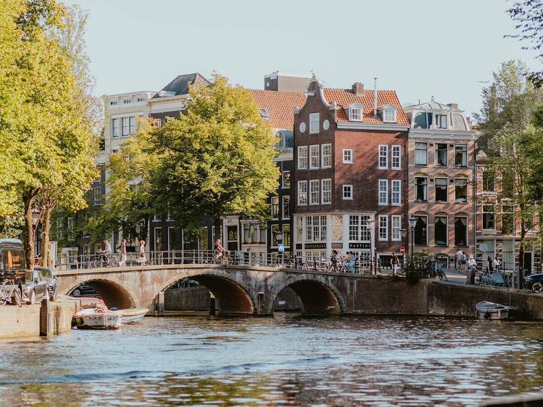 Historic stone bridge spanning an Amsterdam canal lined with narrow houses