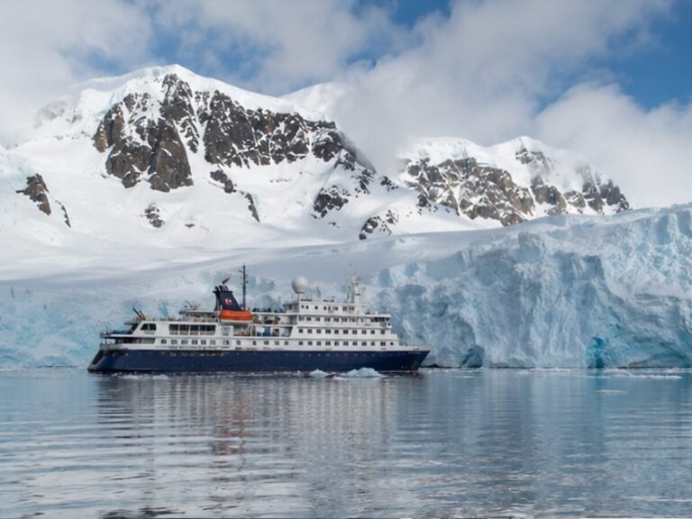 Small expedition cruise ship beside a glacier in Antarctica
