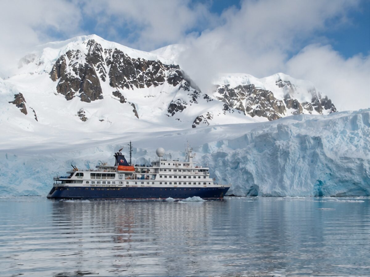 Small expedition cruise ship beside a glacier in Antarctica