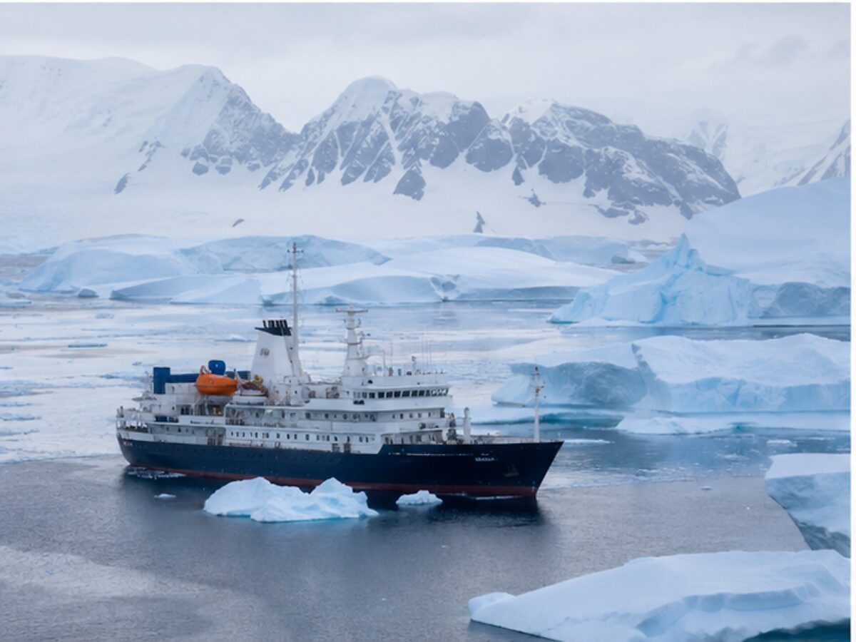 Small ice-strengthened expedition ship sailing among Antarctic icebergs