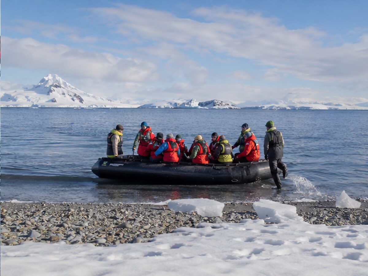 Expedition travelers making a Zodiac landing on a snowy Antarctic beach