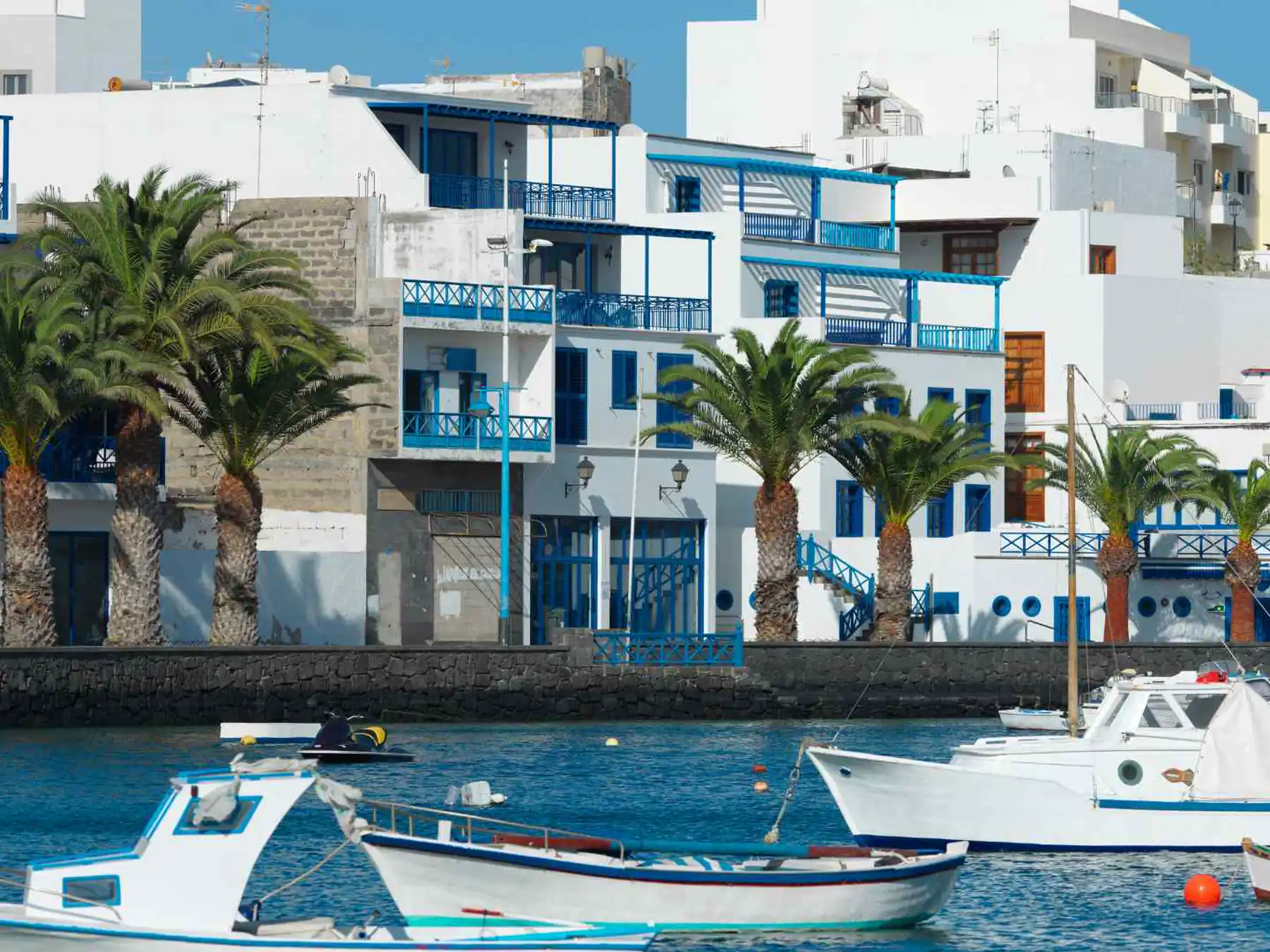 White-and-blue waterfront buildings beside boats in Arrecife.