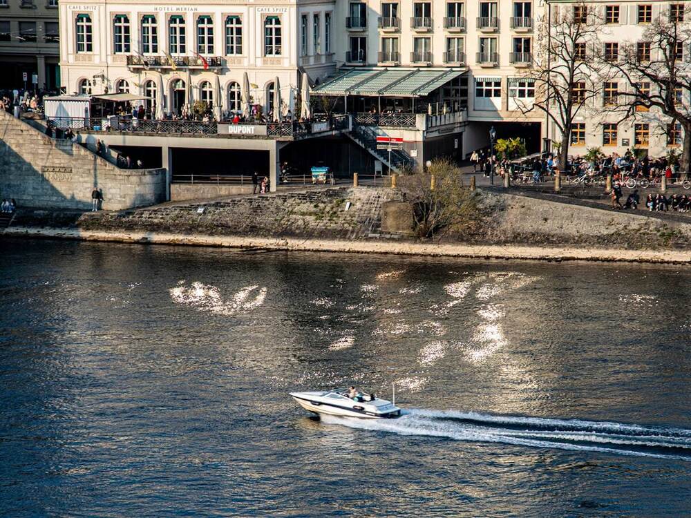 Boat crossing the Rhine beside Basel's riverfront promenade