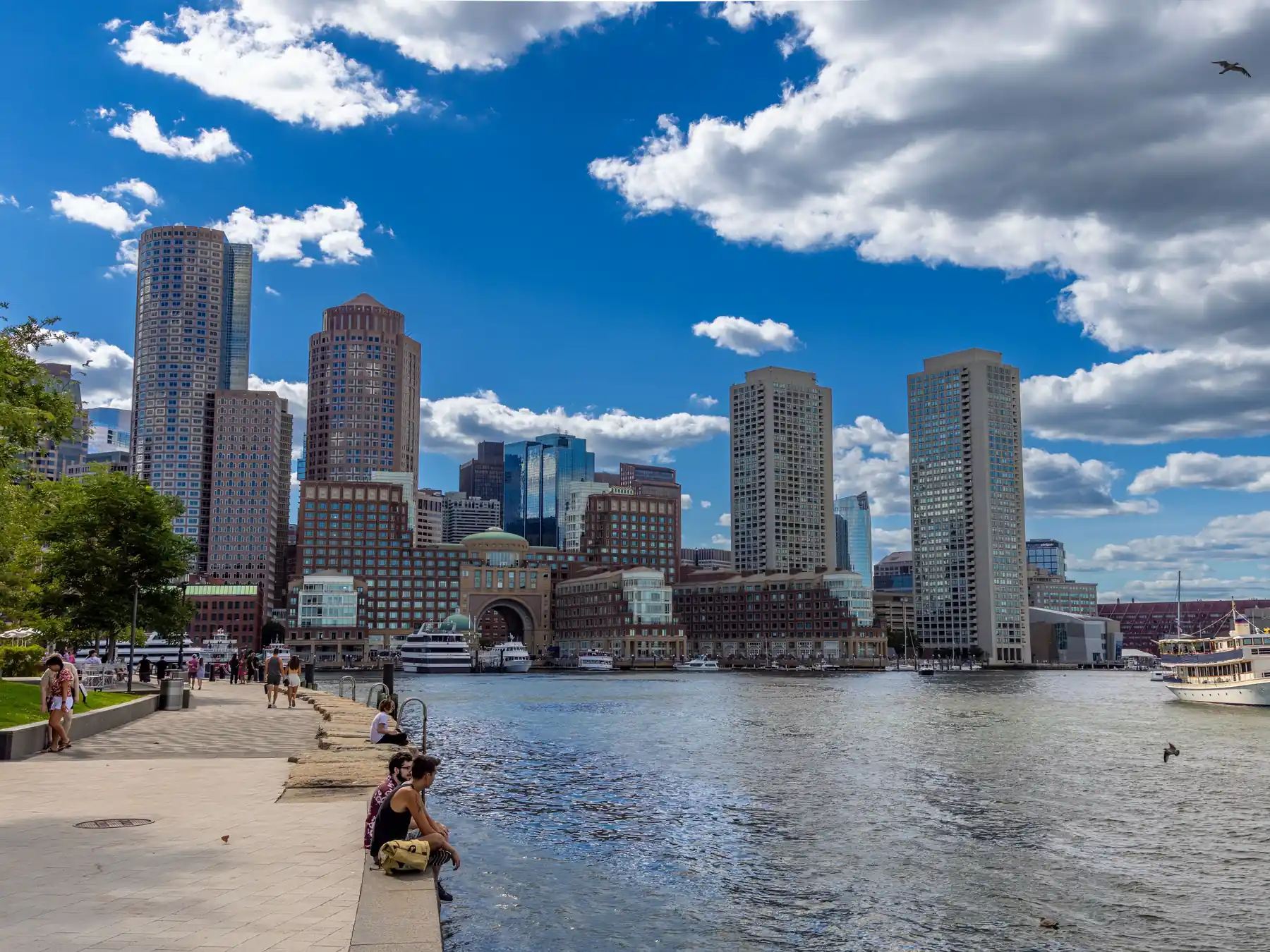 Boston Harbor waterfront and city skyline beneath a clear blue sky.