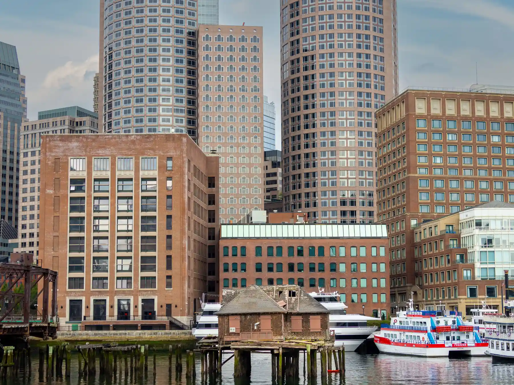 Boston skyline and waterfront buildings reflected in the harbor.