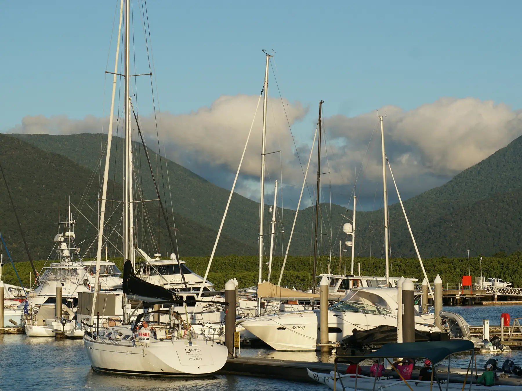 Sailboats moored at Cairns Marlin Marina beneath a cloudy tropical sky.