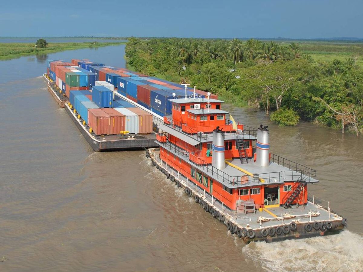 River tug pushing container barges along the Canal del Dique