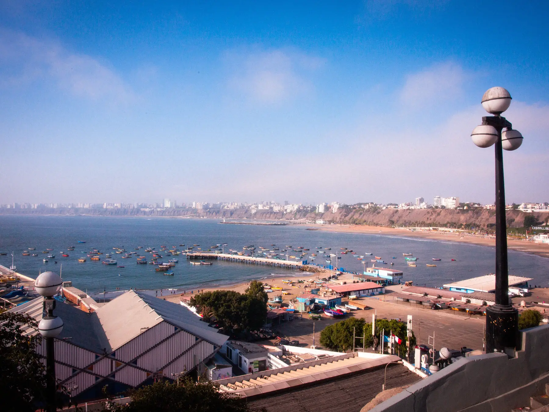 Boats anchored in Callao Bay with the Lima skyline on the horizon.