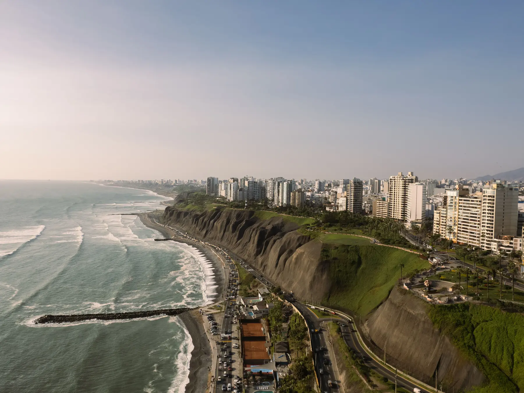 Aerial view of Lima's coastal cliffs, buildings, and the Pacific Ocean.