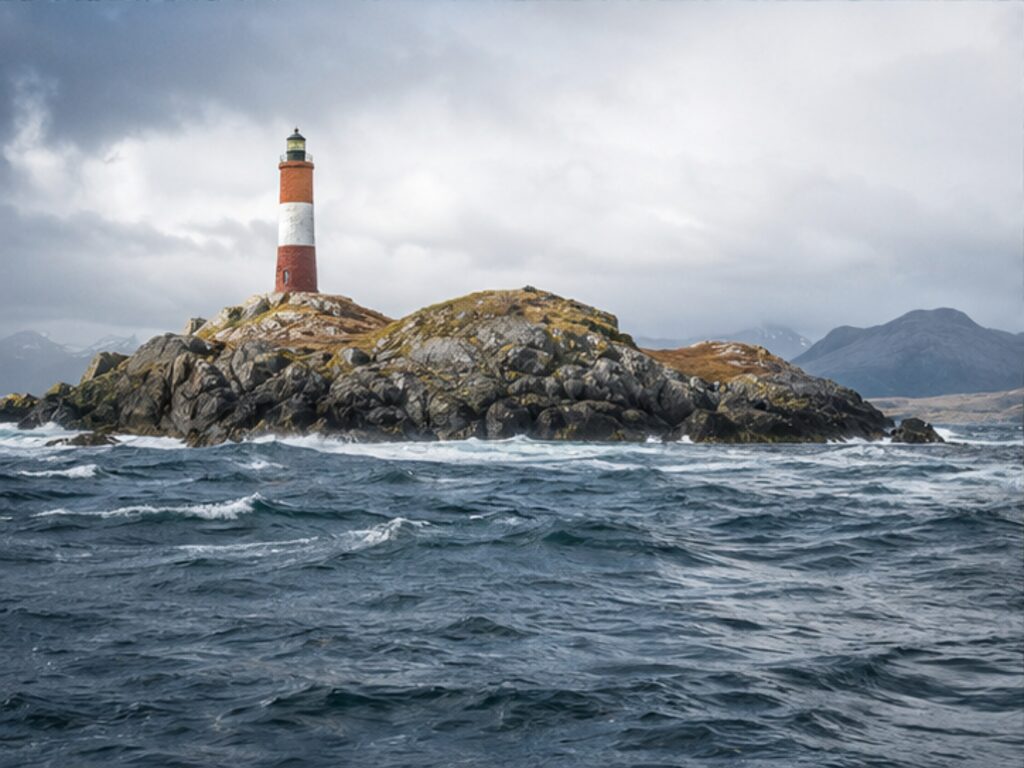 Dramatic rocky coastline and lighthouse at Cape Horn seen from the sea