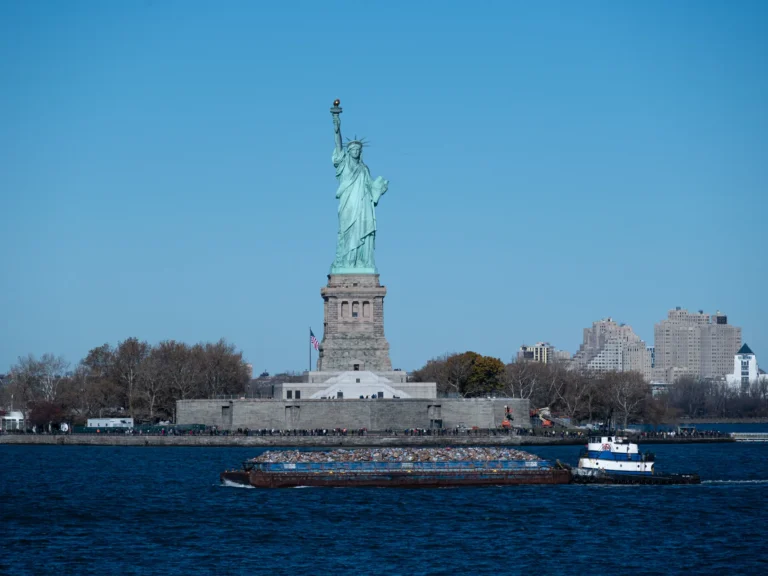 Statue of Liberty and a tugboat in New York Harbor, seen from the New Jersey side.