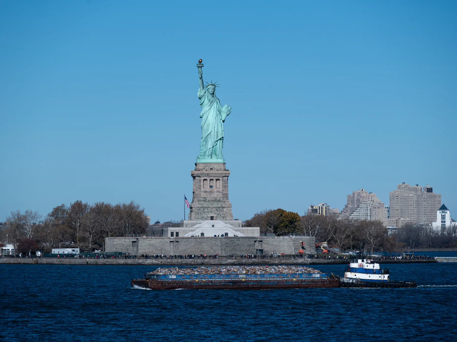 Statue of Liberty and a tugboat in New York Harbor, seen from the New Jersey side.