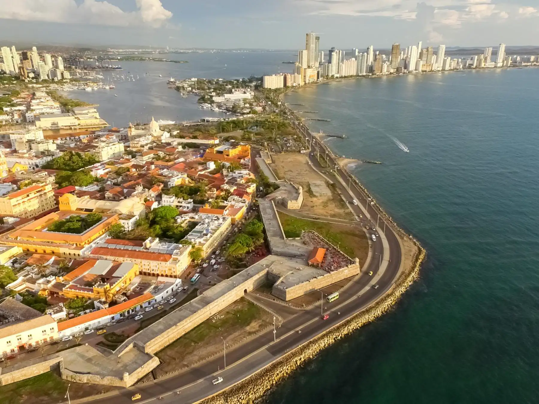 Aerial view of Cartagena's historic walled city beside the Caribbean and modern skyline.