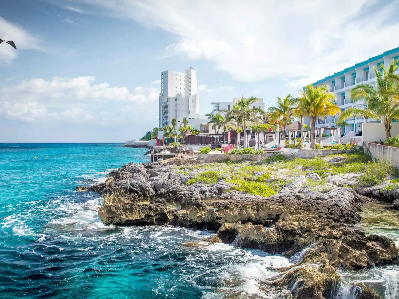 Rocky Cozumel shoreline and waterfront hotels beside blue water