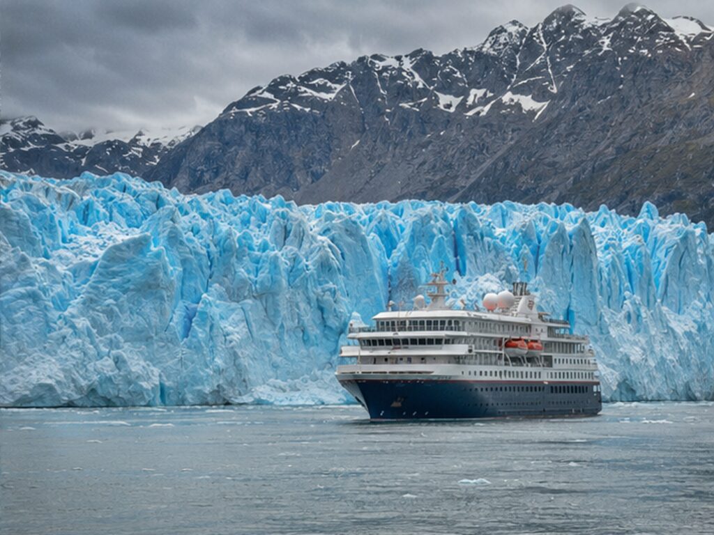 Passenger ship facing a blue tidewater glacier in the Chilean fjords