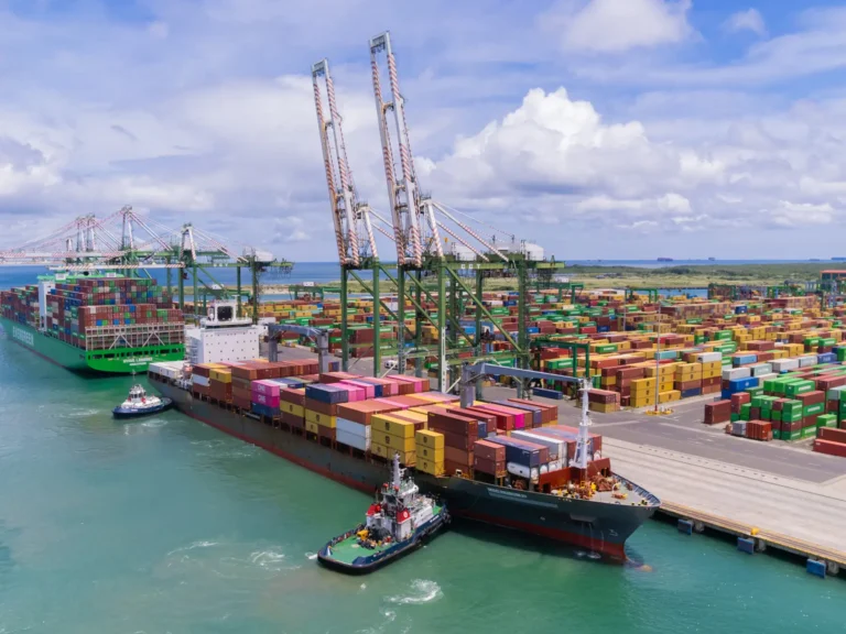 A container ship and tugboats at a working terminal in Colón, Panama.