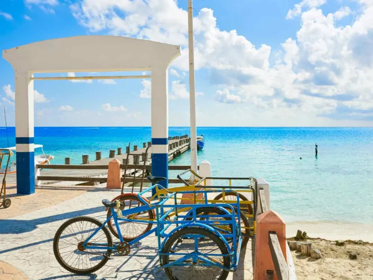 Bicycles parked beside a bright Costa Maya beach