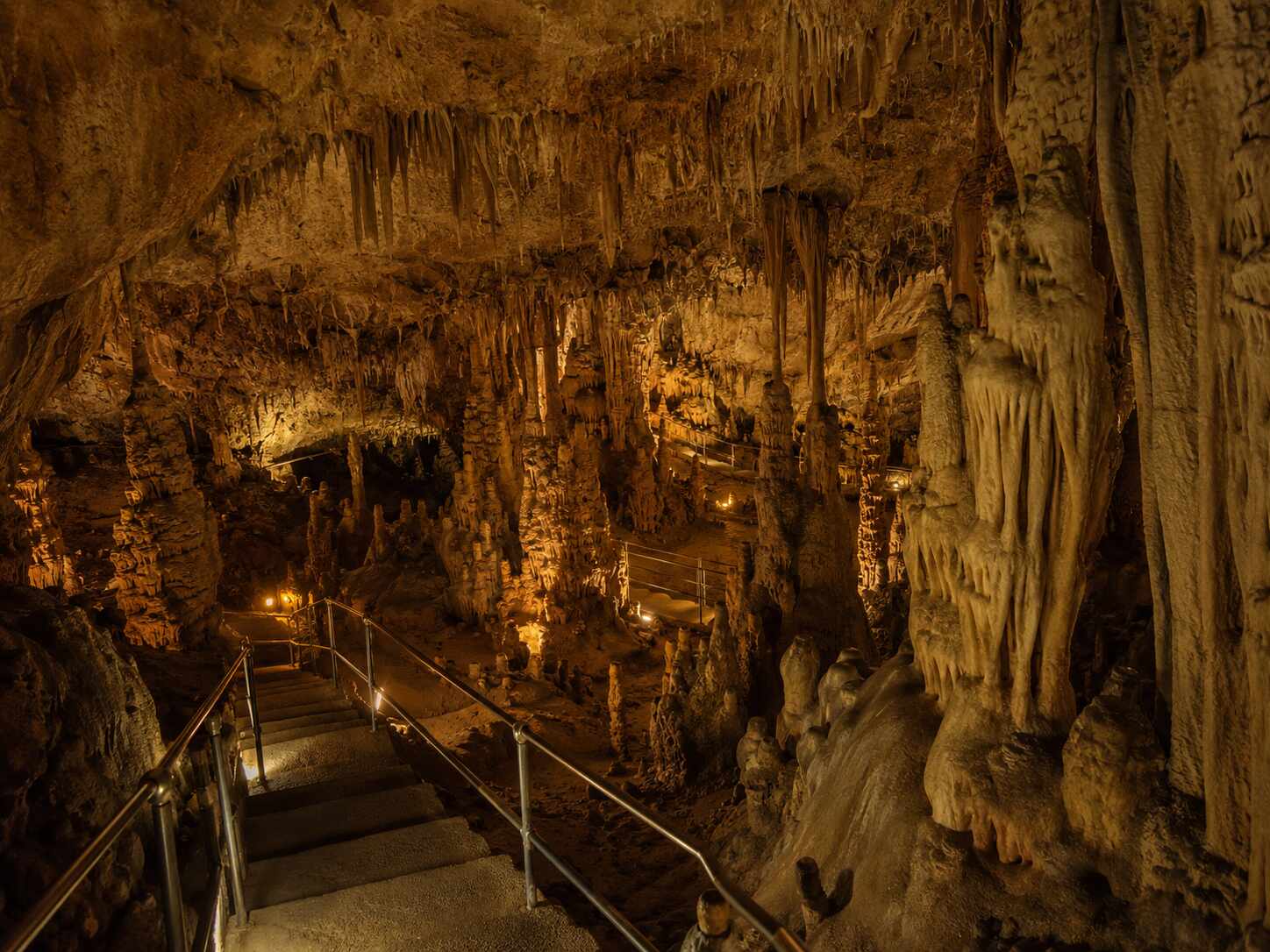 Stalactites, stalagmites and illuminated visitor path inside Damlataş Cave in Alanya