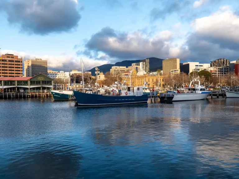 Boats moored along the Hobart waterfront with the city skyline behind them.
