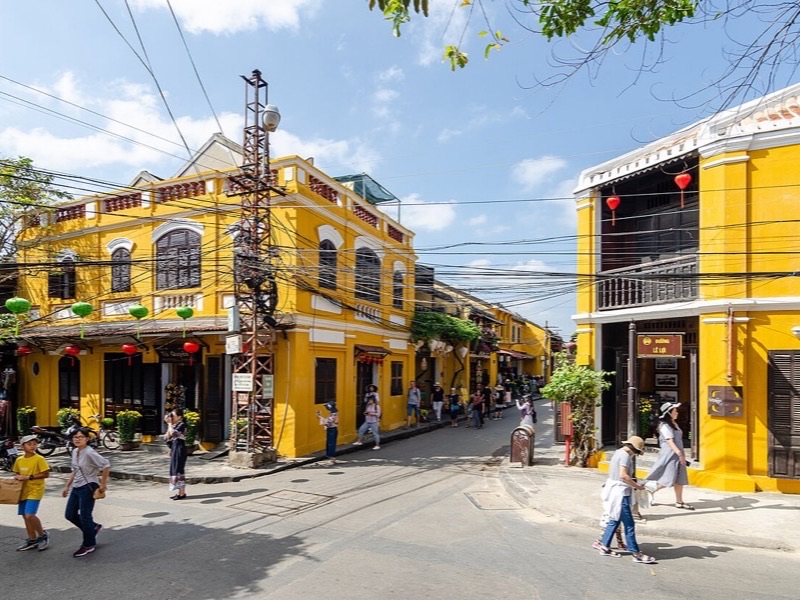 Yellow heritage buildings and lanterns on a sunny street in Hội An Ancient Town