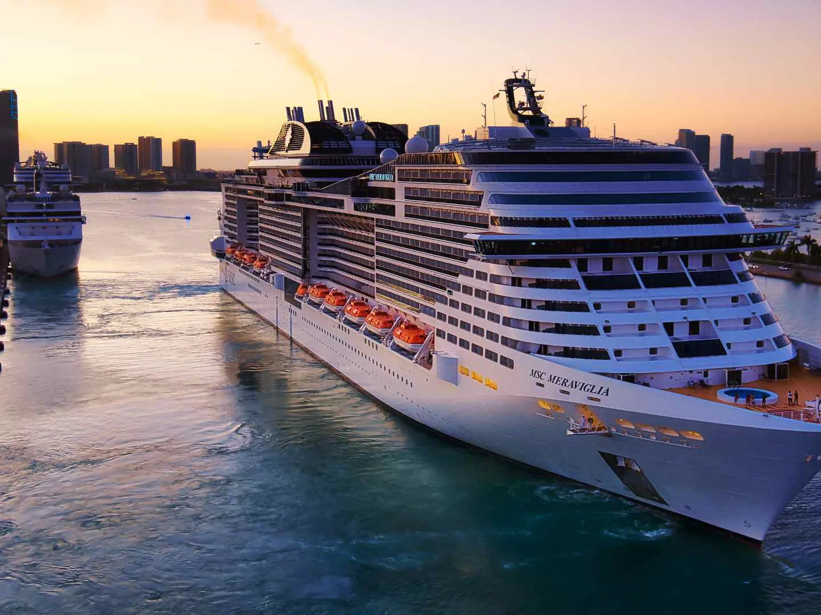 Several cruise ships maneuvering through a busy harbor at sunset