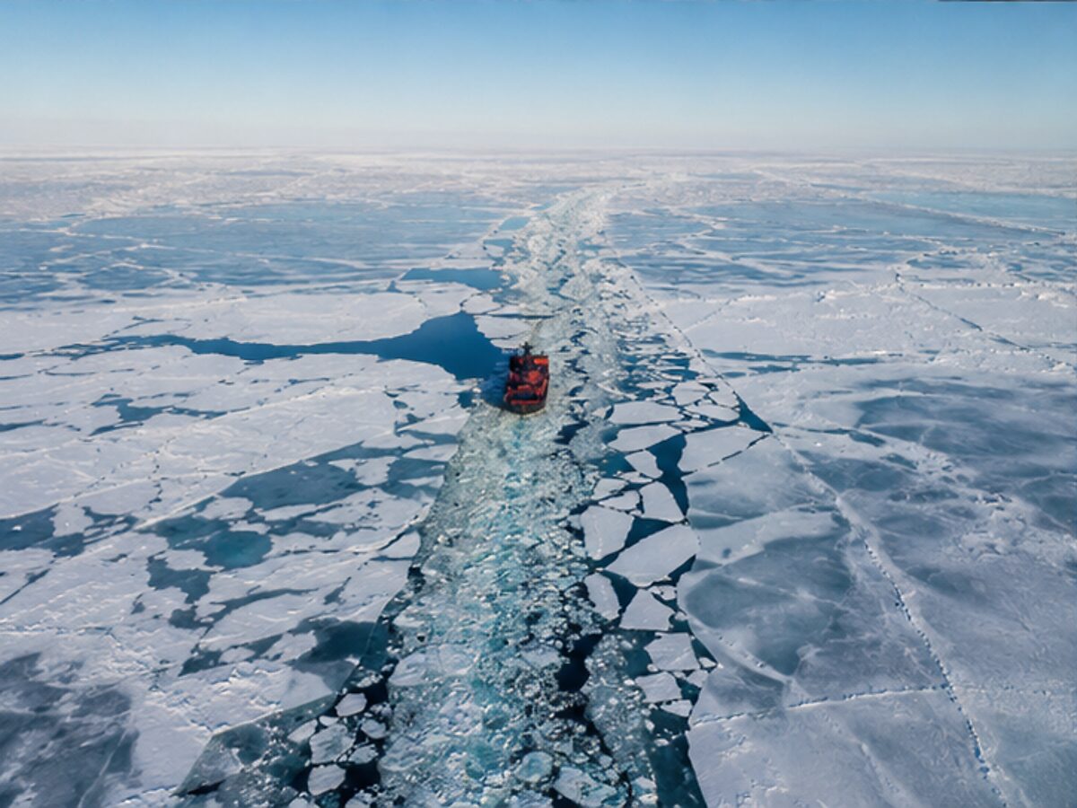 Aerial view of an icebreaker carving a route through fractured Arctic sea ice