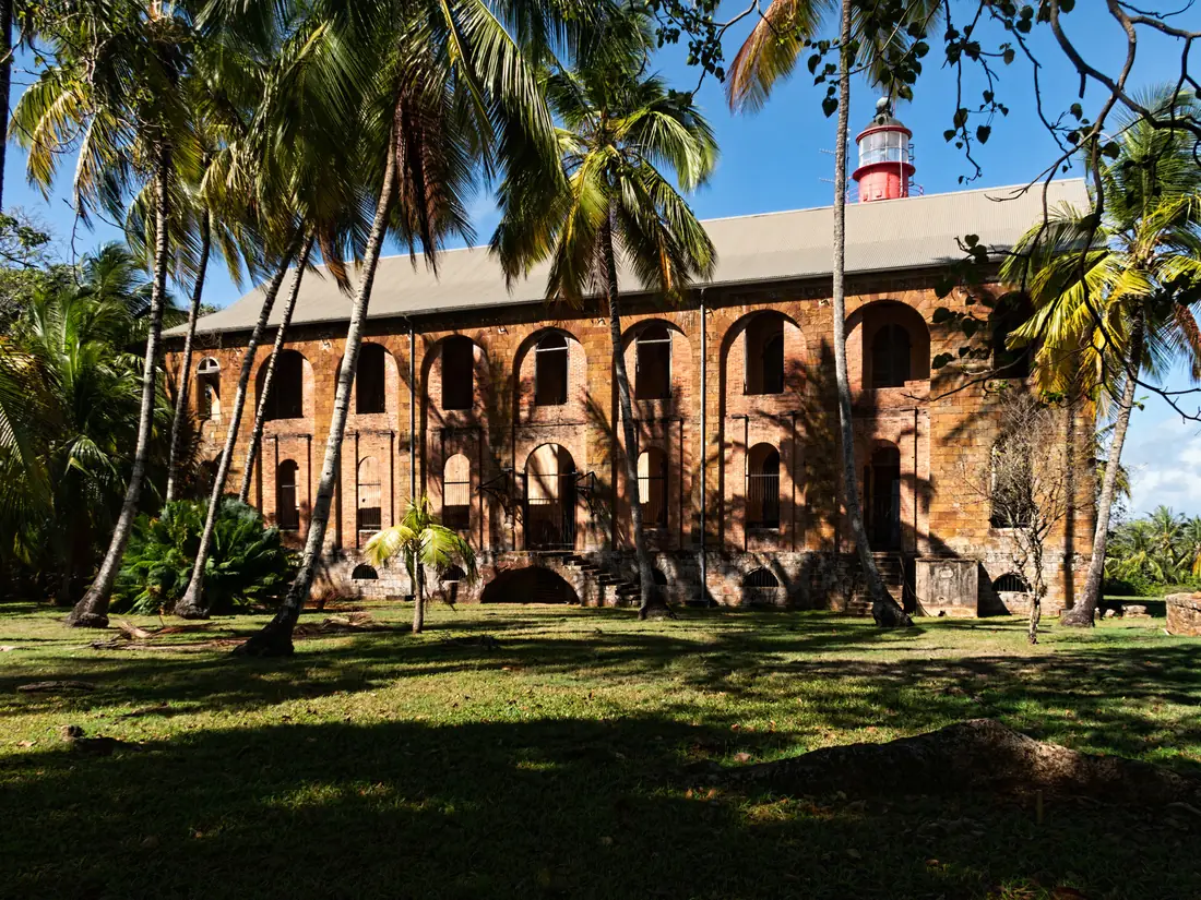 Former prison hospital surrounded by palm trees on Île Royale
