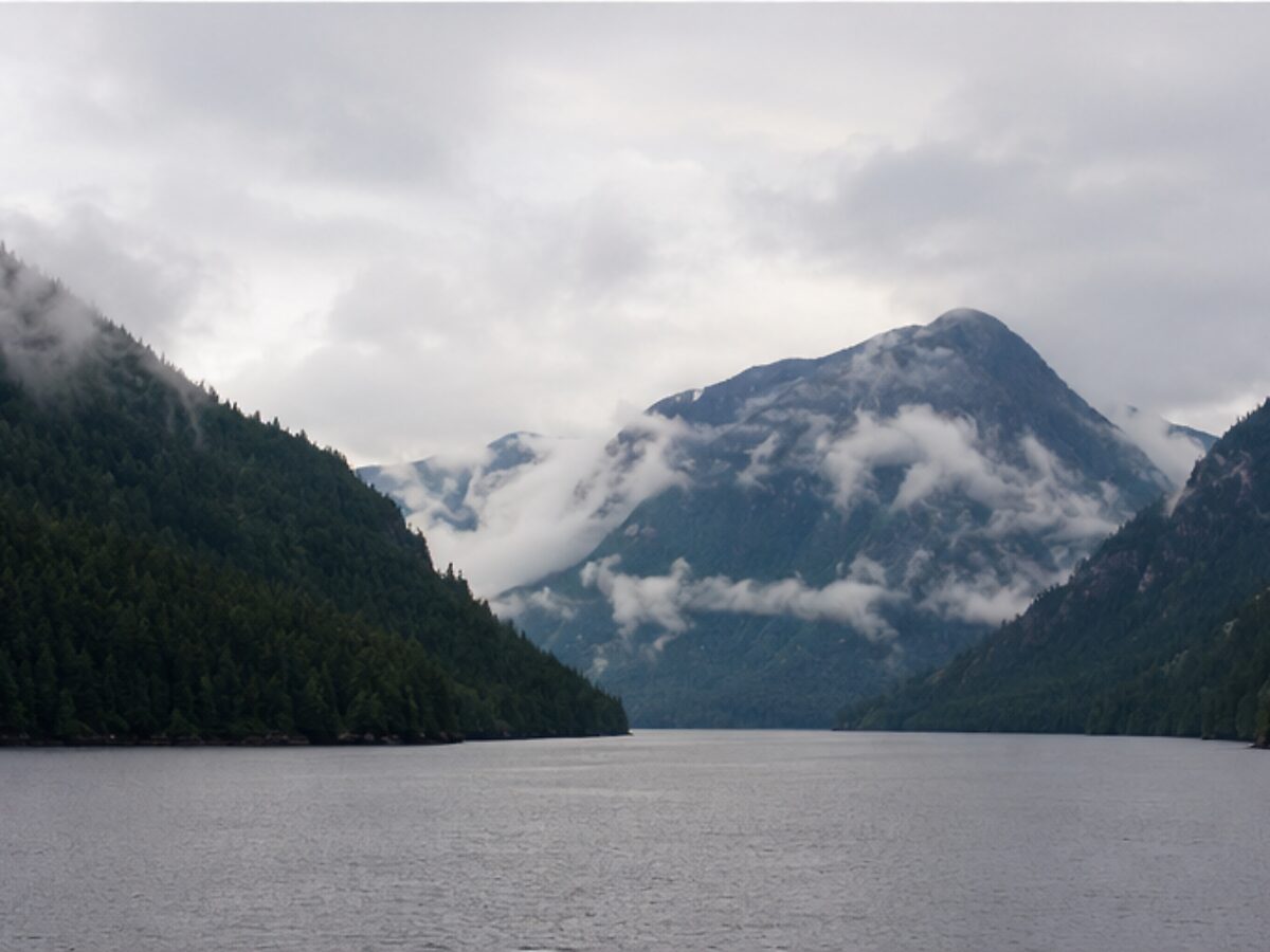 Misty forested mountains along a narrow channel of British Columbia's Inside Passage