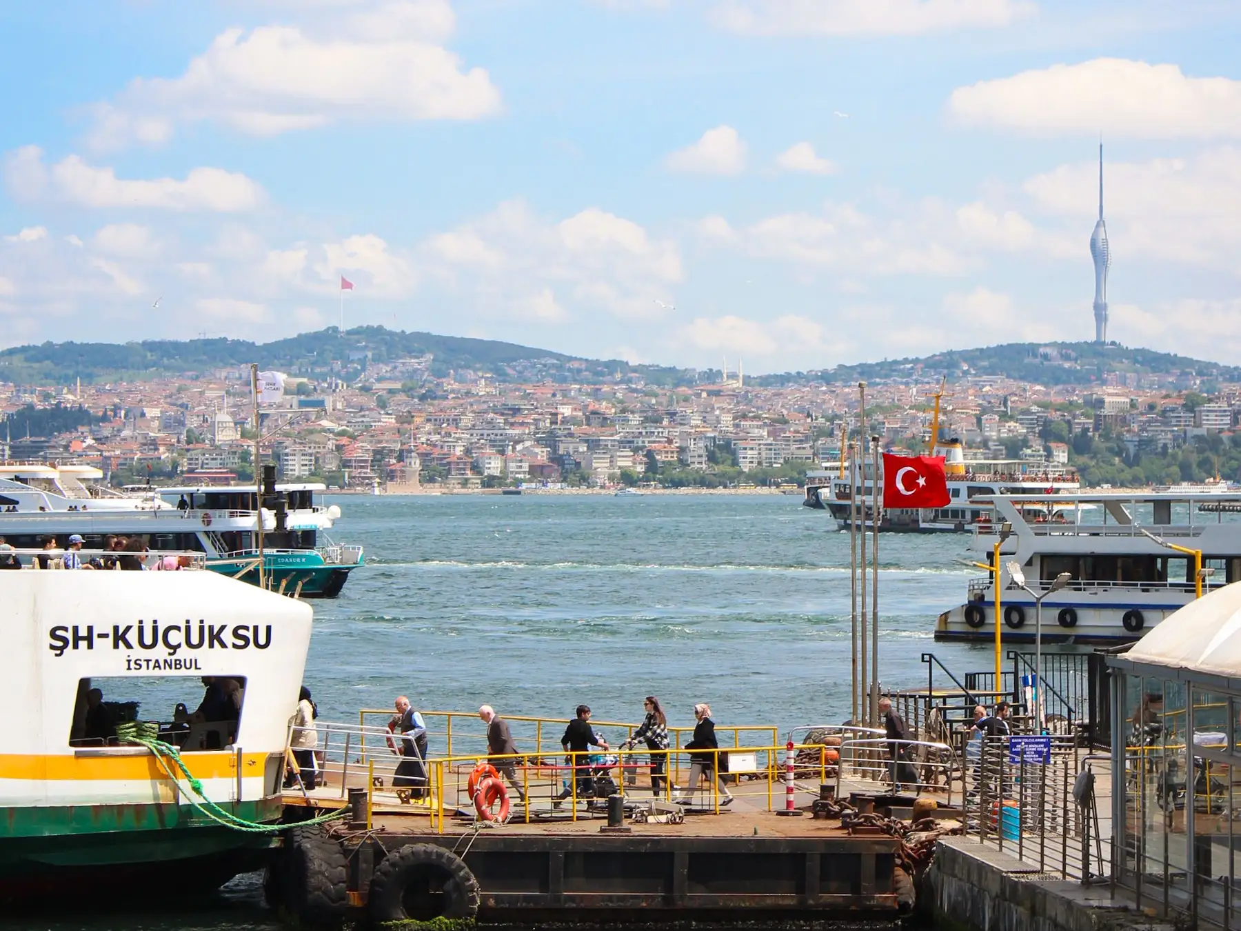 Passenger ferry at an Istanbul dock with the Bosphorus and city skyline beyond.