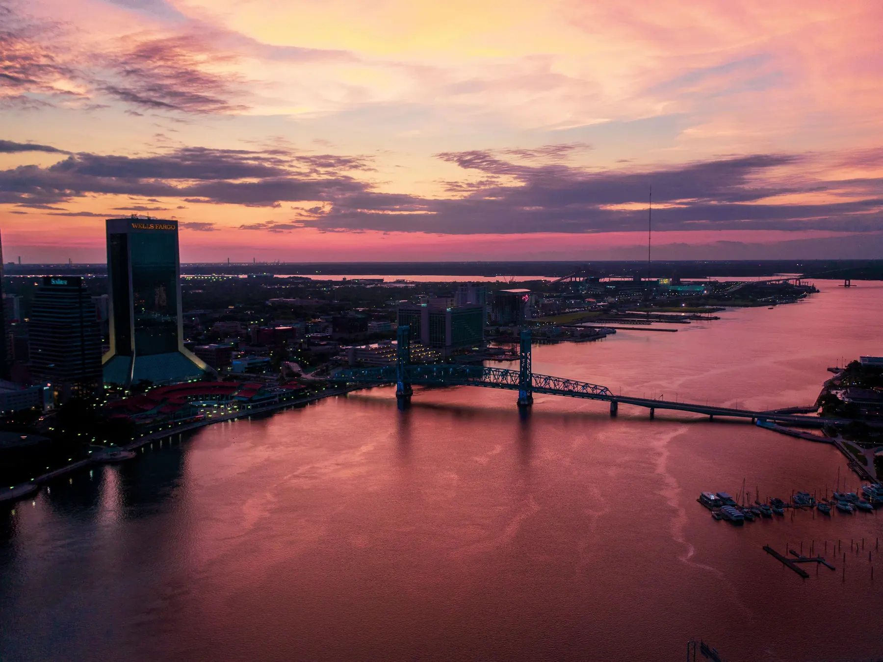 Downtown Jacksonville skyline glowing above the St. Johns River at sunset.