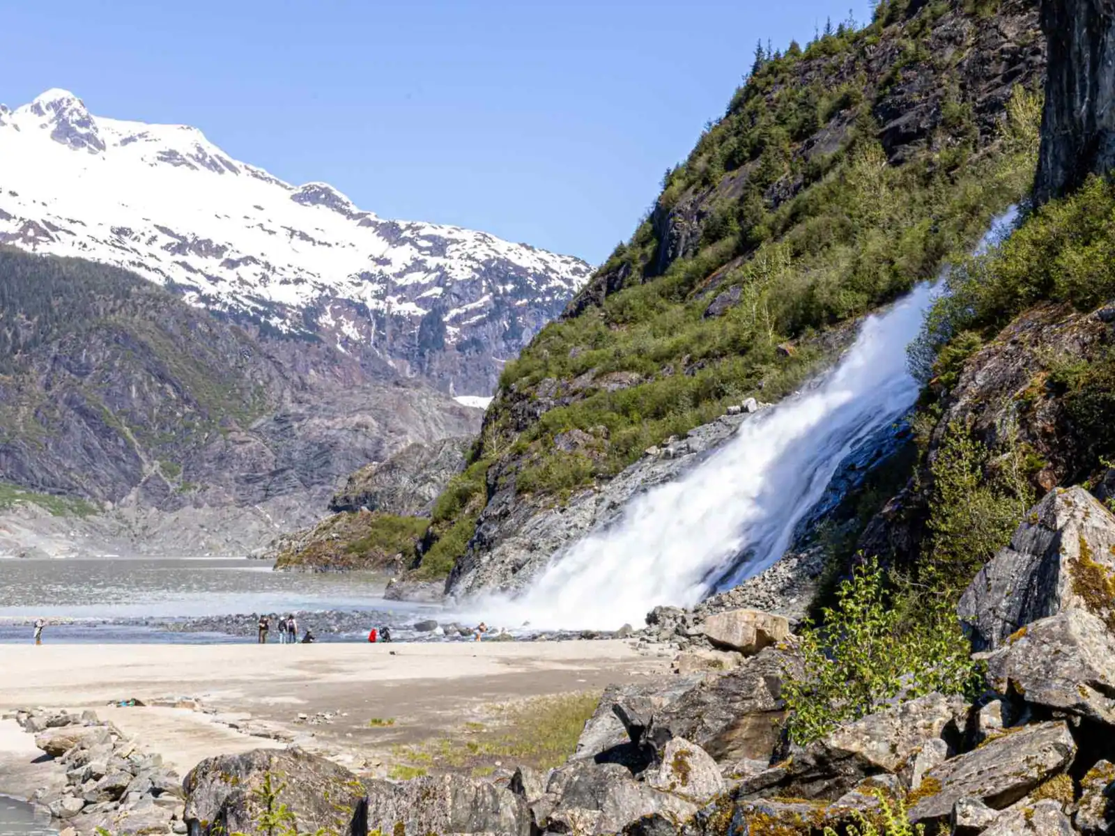 Waterfall descending beside a glacier near Juneau