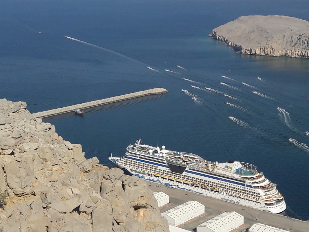 Cruise ship docked at Khasab port below the rocky Musandam cliffs